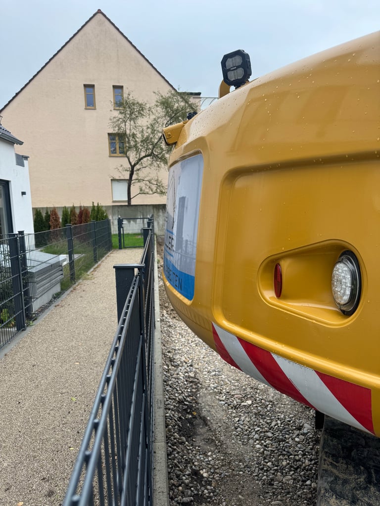 Yellow emergency service vehicle parked next to residential house with metal fence and gravel driveway