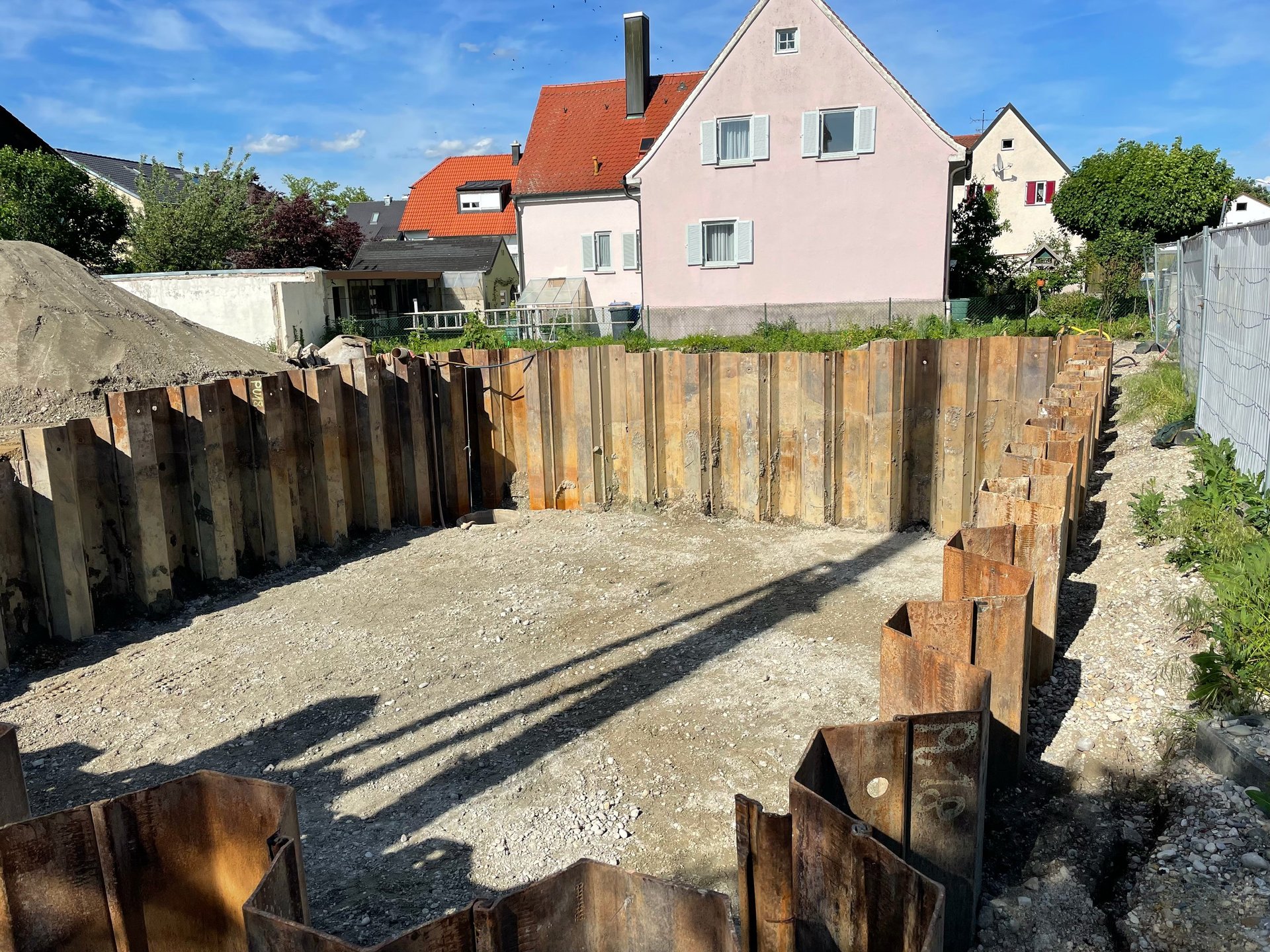 Residential house with wooden piling foundation and metal support posts under construction, surrounded by gravel base