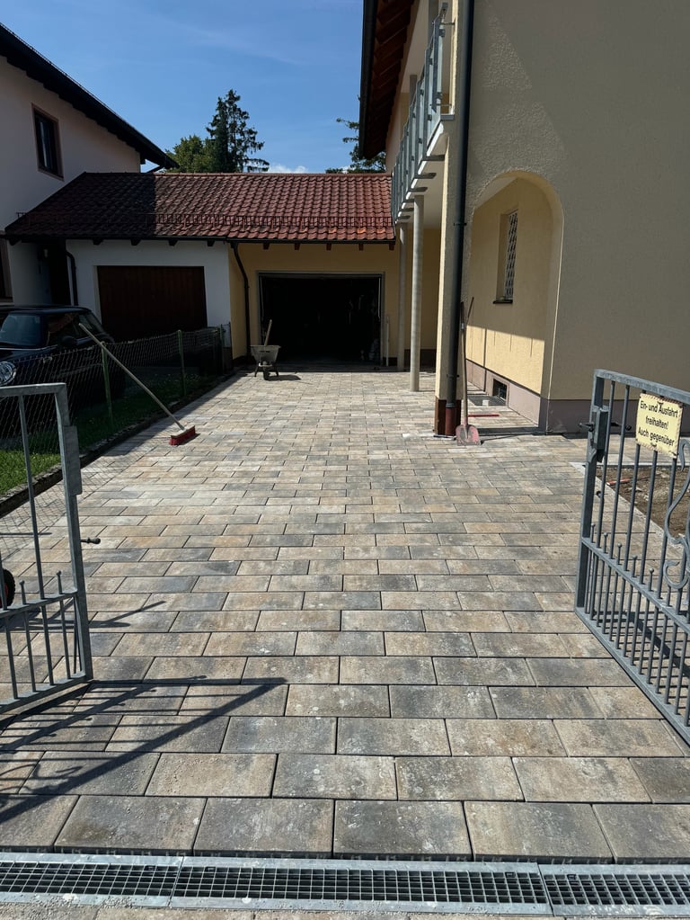 New paved driveway with brick pattern leading to double garages and cream-colored house