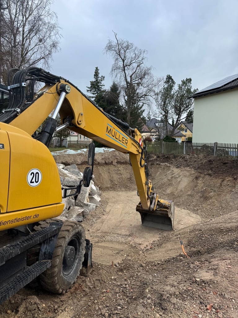 Yellow Muller excavator with number 20 on residential construction site with bare trees and houses in background